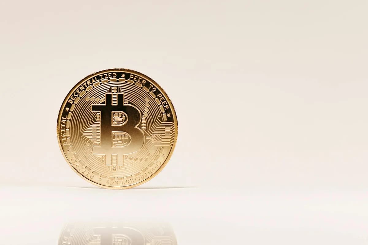 BRICS Crypto Implications: A Beginner's Guide Close-up of a golden Bitcoin coin standing upright on a neutral background, showcasing cryptocurrency symbolism.